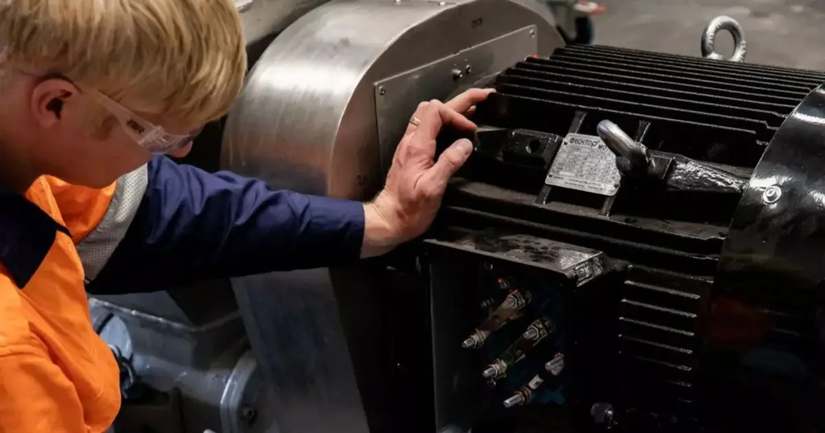 Technician in hi-vis workwear inspecting the terminal box of a large electric motor