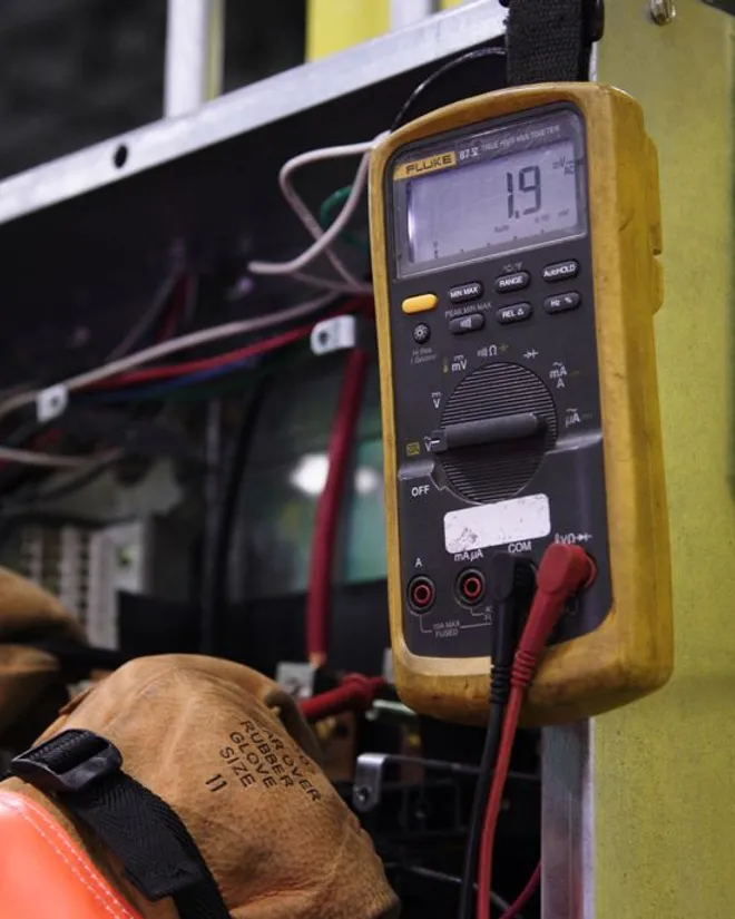 Controls technician taking a reading with a Fluke meter on an electrical panel