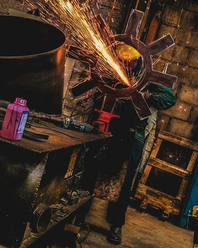 Maintenance welder cutting a steel part with a shower of sparks